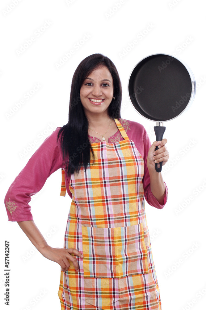 Young Indian woman holding kitchen utensil against white Young Indian woman holding kitchen utensil against white