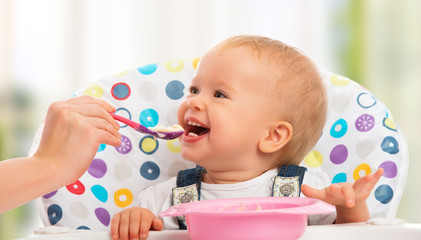 happy mother feeds funny  baby from  spoon