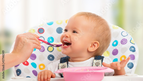happy mother feeds funny  baby from  spoon