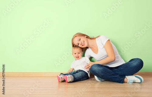 happy family of mother and child sitting on the floor in an empt