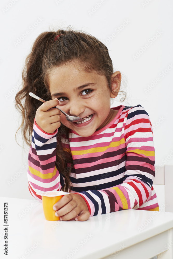 Young girl eating yoghurt in studio