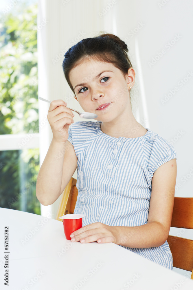 Young girl eating yoghurt, looking away Young girl eating yoghurt, looking away
