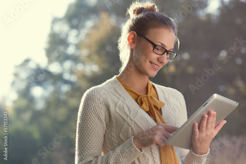 happy woman in glasses using tablet pc in the park