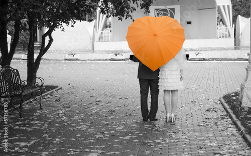 Newlyweds under an orange umbrella