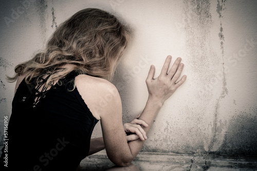 one sad woman sitting on the floor near a wall