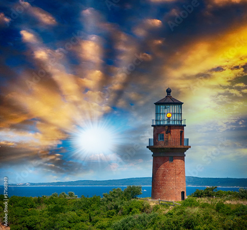 Lighthouse on a beautiful island. Sunset view with trees and sea photo