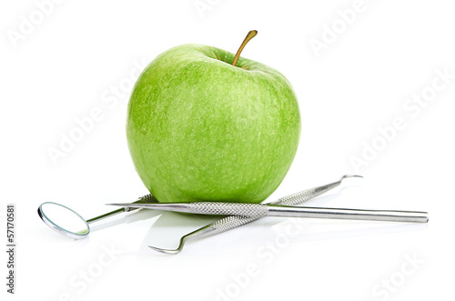 Green apple and dental tools isolated on white