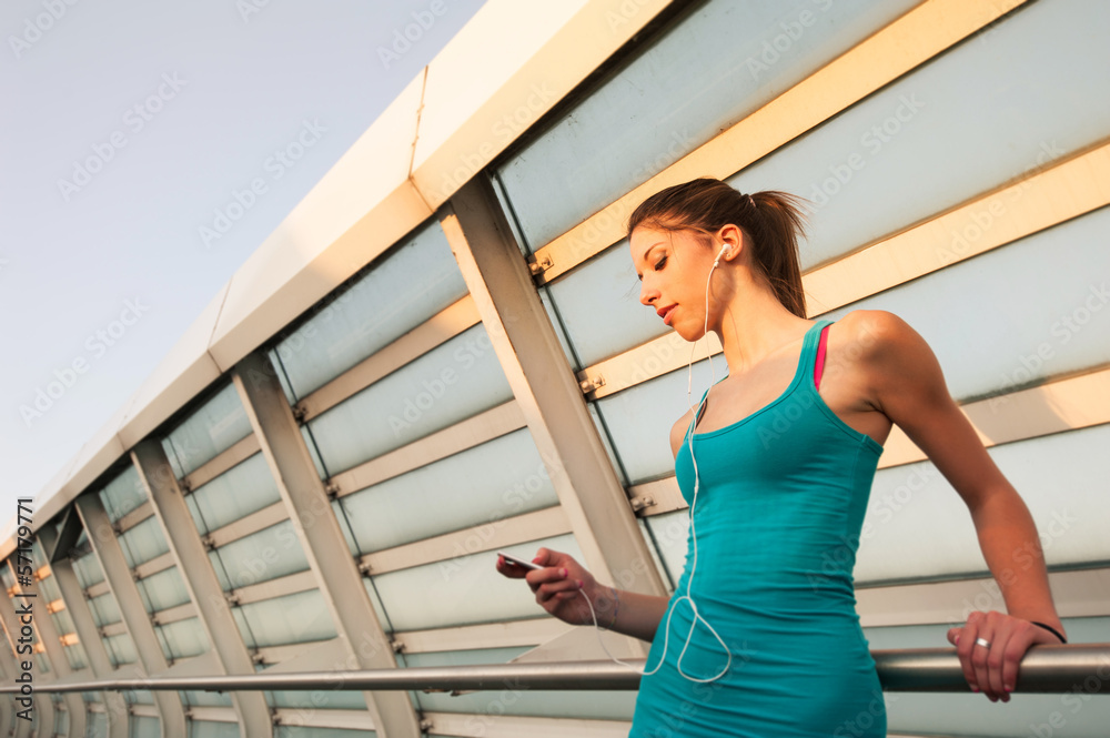 Young woman relaxing outdoors on a modern bridge while listening