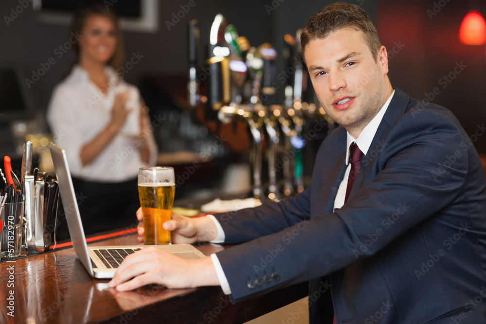 Businessman having a pint while working on his laptop Businessman having a pint while working on his laptop