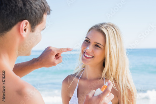 Man putting sun cream on smiling girlfriends nose
