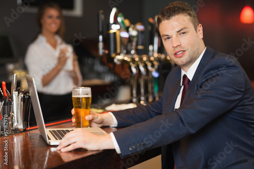 Businessman having a pint while working on his laptop