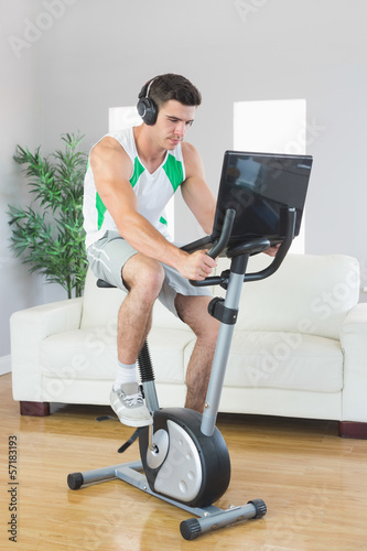 Serious handsome man training on exercise bike using laptop © WavebreakmediaMicro