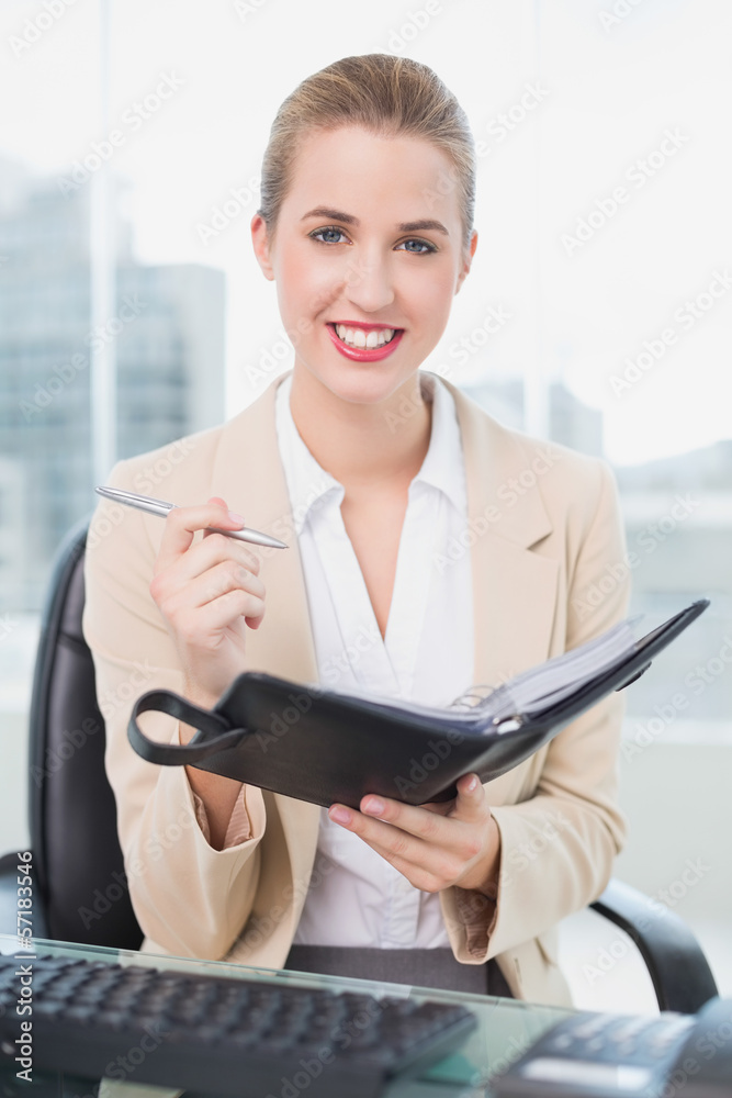 Smiling attractive businesswoman writing on her agenda Smiling attractive businesswoman writing on her agenda