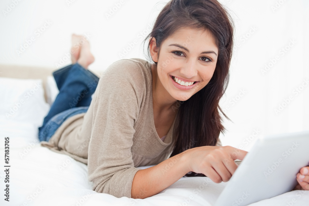 Woman uses tablet as she smiles looking straight ahead, while ly Woman uses tablet as she smiles looking straight ahead, while ly