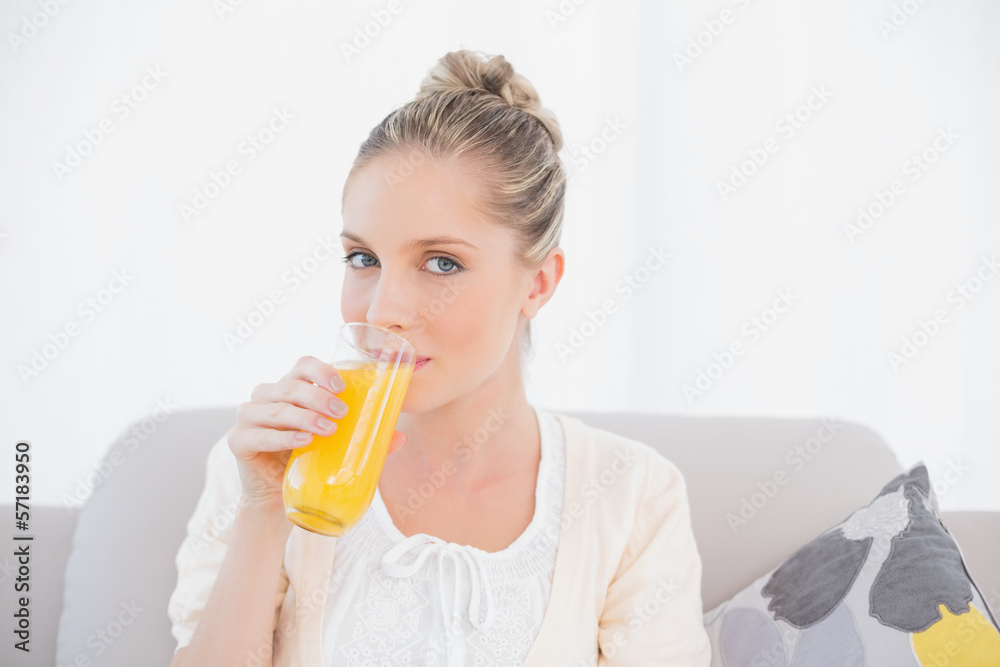 Gorgeous model drinking orange juice sitting on sofa Gorgeous model drinking orange juice sitting on sofa