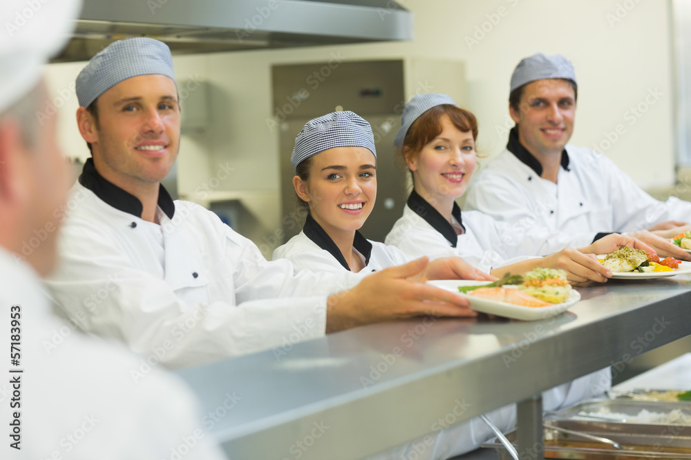 Young chefs presenting some plates to the head chef