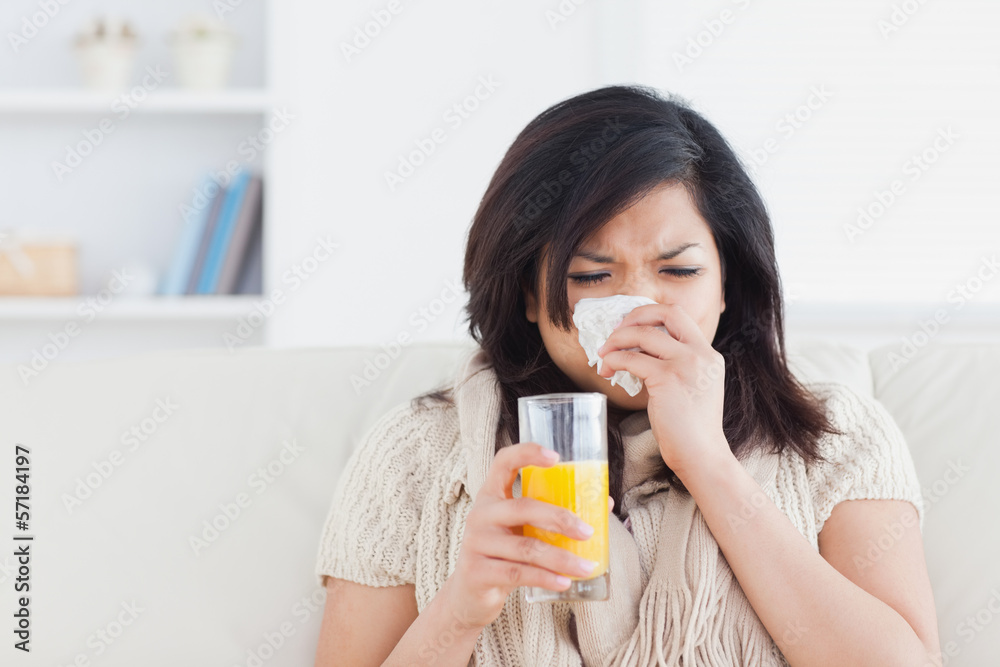 Sneezing woman drinking a glass of orange juice Sneezing woman drinking a glass of orange juice