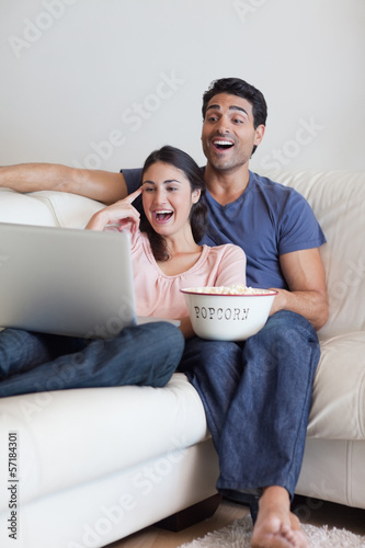 Portrait of a laughing couple watching a movie while eating popc photo