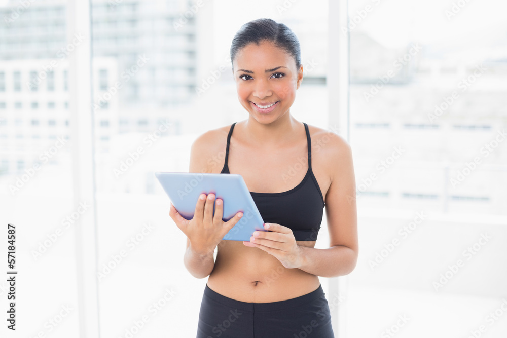 Charming dark haired model in sportswear holding a tablet pc Charming dark haired model in sportswear holding a tablet pc