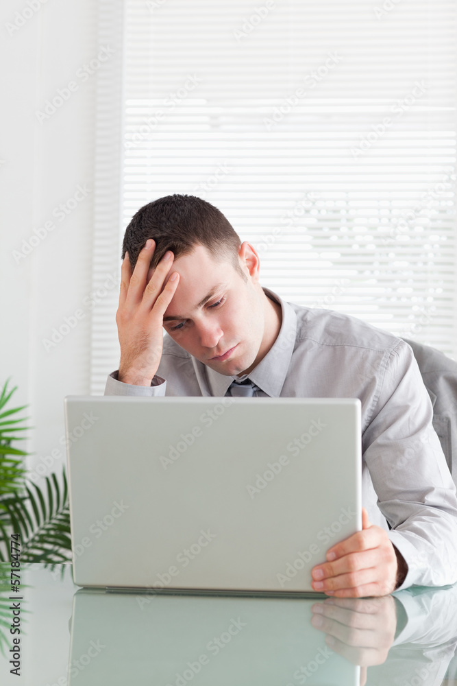Close up of disappointed businessman looking at his laptop Close up of disappointed businessman looking at his laptop