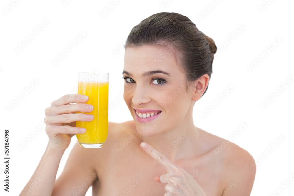 Amused natural brown haired model showing her glass of orange ju