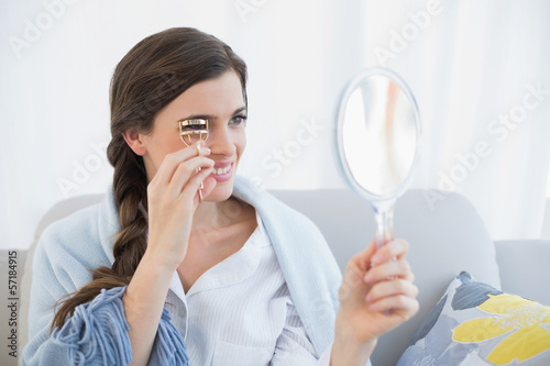 Concentrated casual brown haired woman in white pajamas using an photo