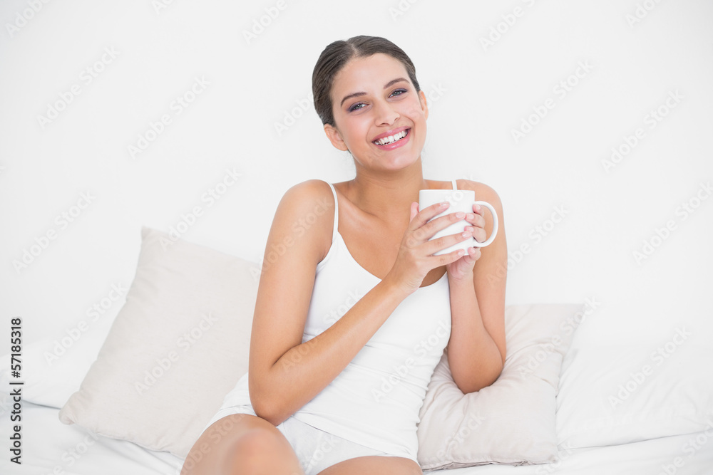 Attractive young brown haired model in white pajamas drinking co Attractive young brown haired model in white pajamas drinking co