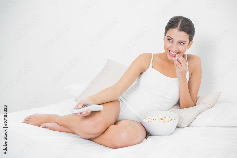 Attentive young brown haired model eating popcorn while watching Attentive young brown haired model eating popcorn while watching