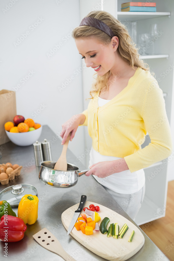 Cheerful cute blonde stirring with wooden spoon