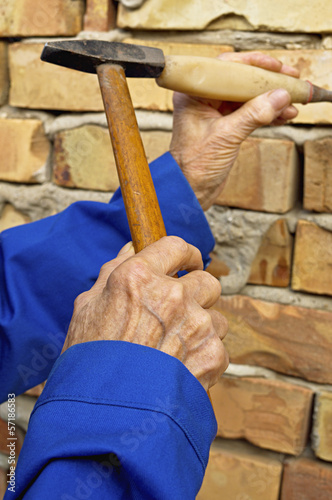 Elderly hands with a hammer and chisel.