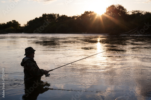 Fisherman catches of salmon at sunset © Stanislav Komogorov