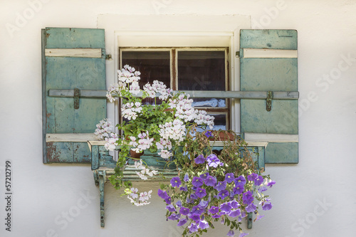 Dekoratives Blumenfenster an einem Bauernhaus photo