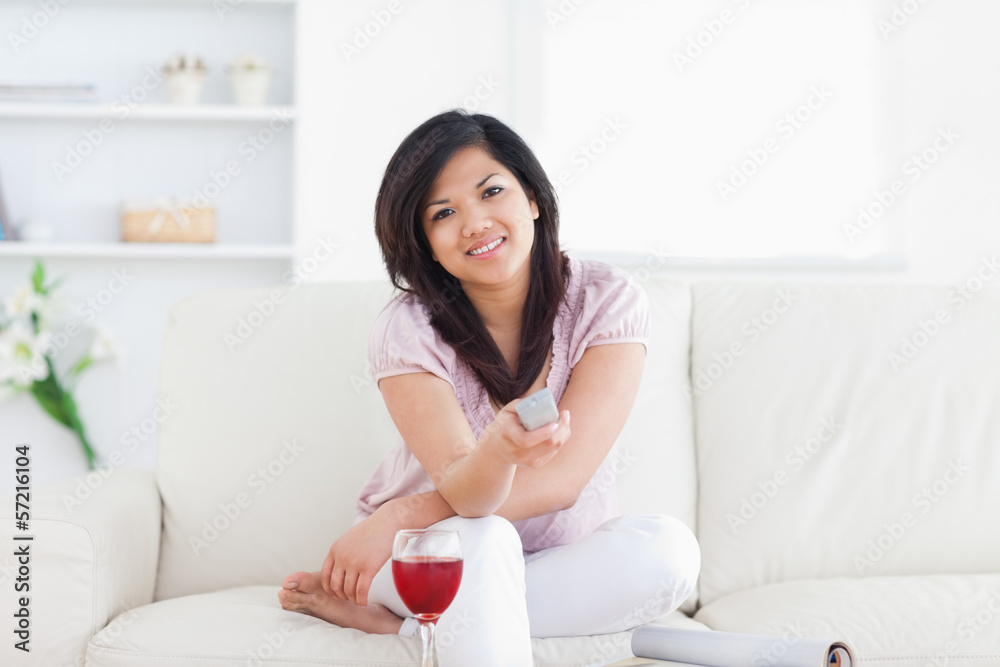 Woman sitting on a couch and holding a television remote