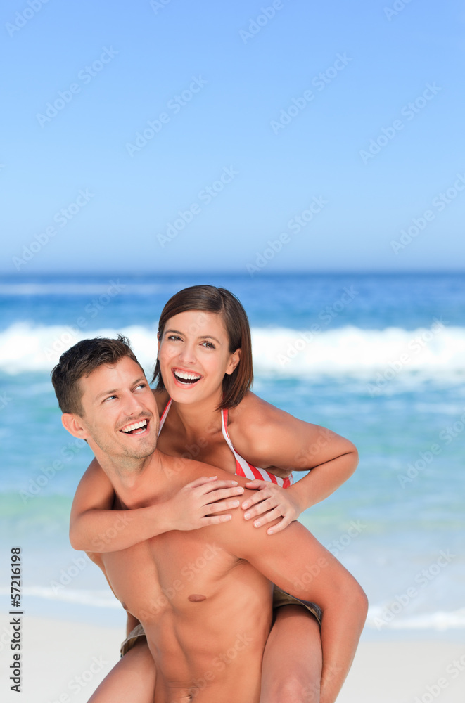 Handsome man having wife a piggyback on the beach Handsome man having wife a piggyback on the beach