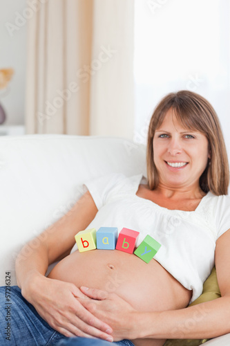Fotografía Lovely pregnant woman playing with wooden blocks while lying on