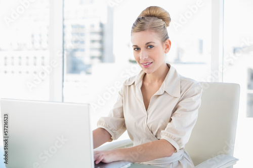 Stern young blonde businesswoman using a laptop