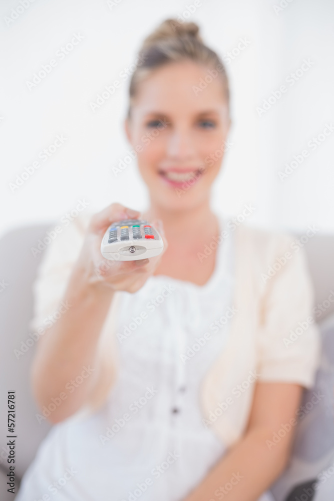 Smiling fresh model changing tv channel sitting on sofa Smiling fresh model changing tv channel sitting on sofa