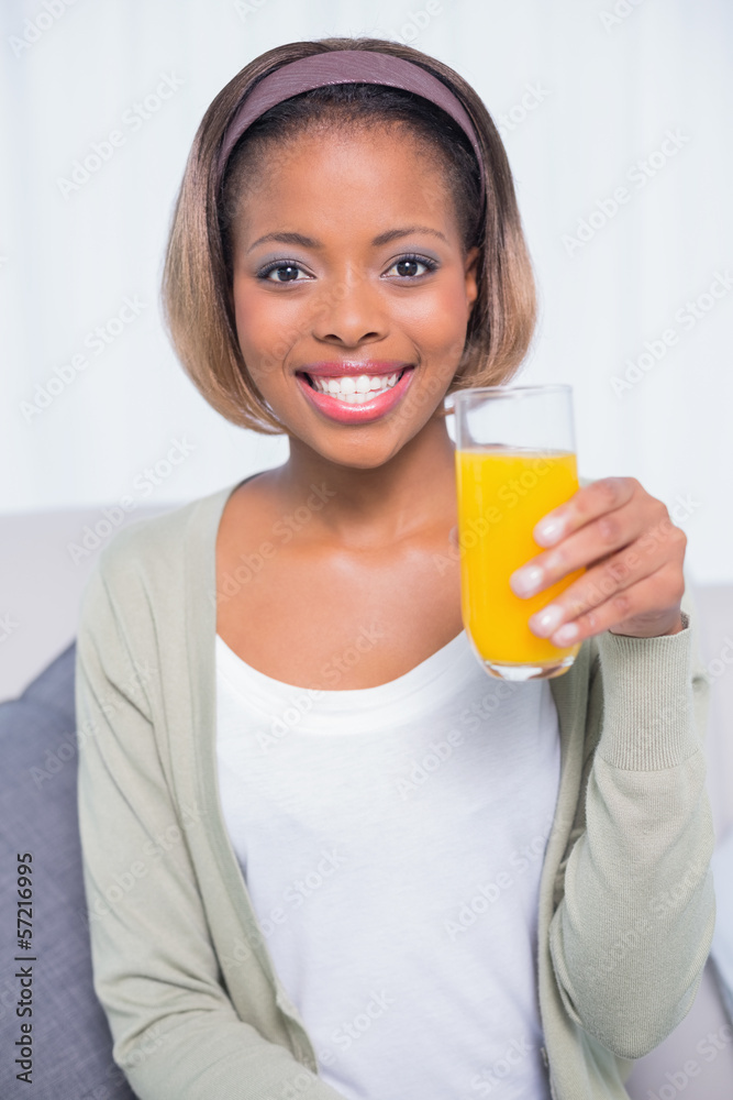 Pretty woman sitting on sofa holding orange juice Pretty woman sitting on sofa holding orange juice