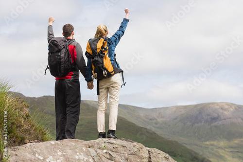 Excited couple reaching the top of their hike and cheering