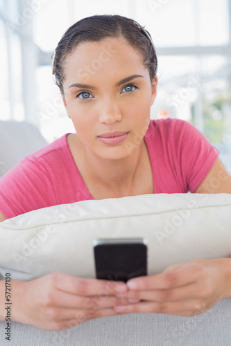 Serious woman lying on sofa and texting