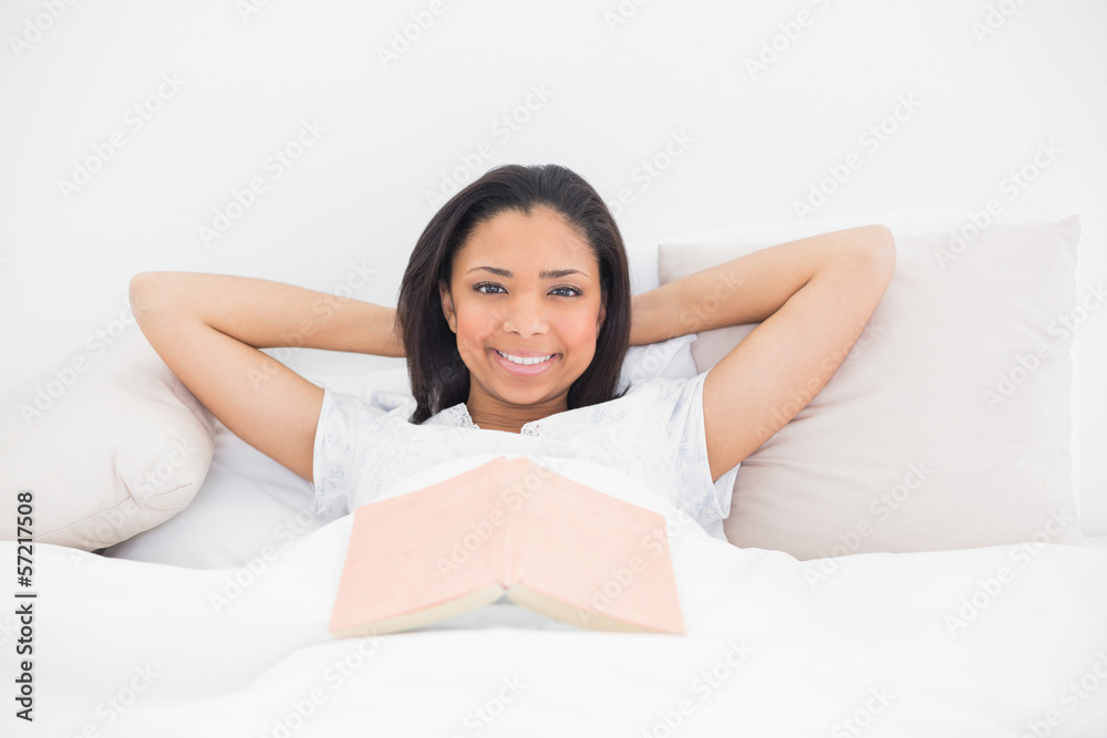 Smiling young dark haired model relaxing in her bed Smiling young dark haired model relaxing in her bed