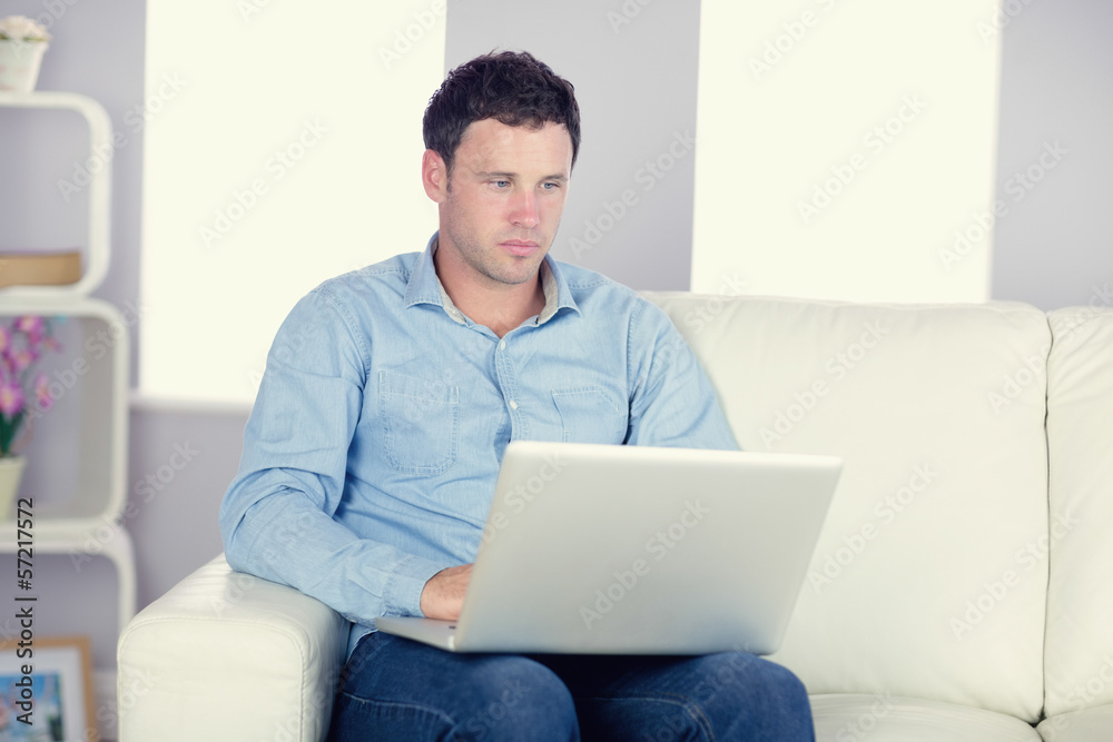 Attractive casual man sitting on couch using laptop Attractive casual man sitting on couch using laptop