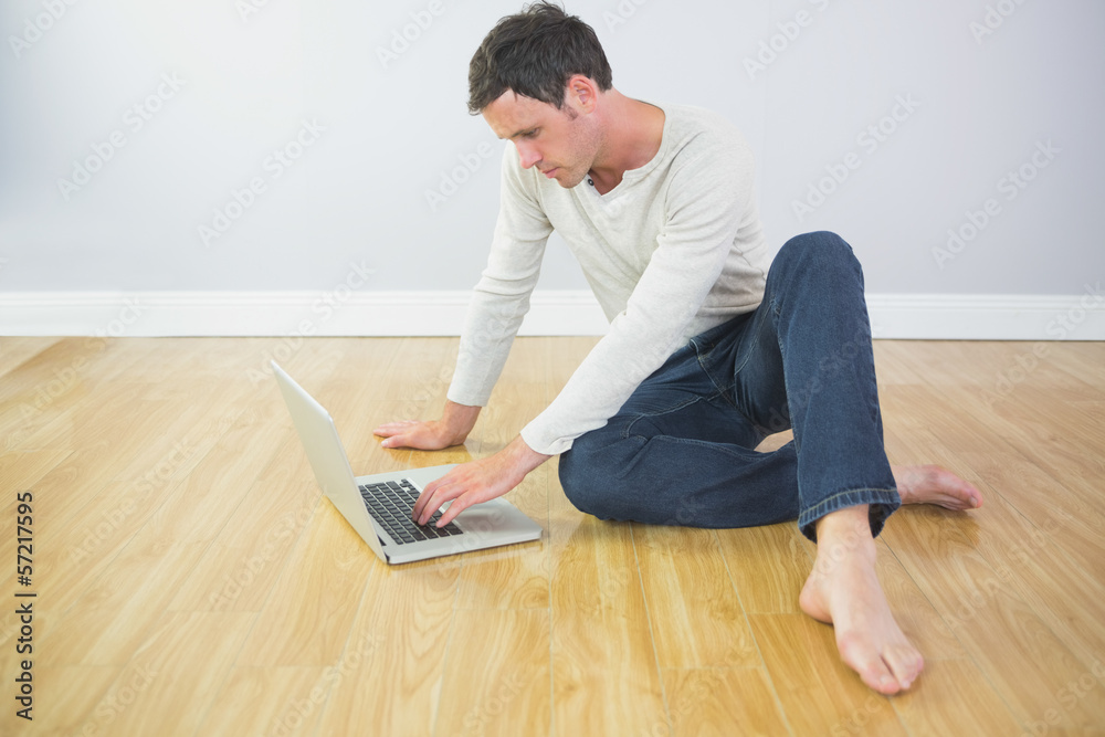 Casual calm man sitting on floor using laptop Casual calm man sitting on floor using laptop