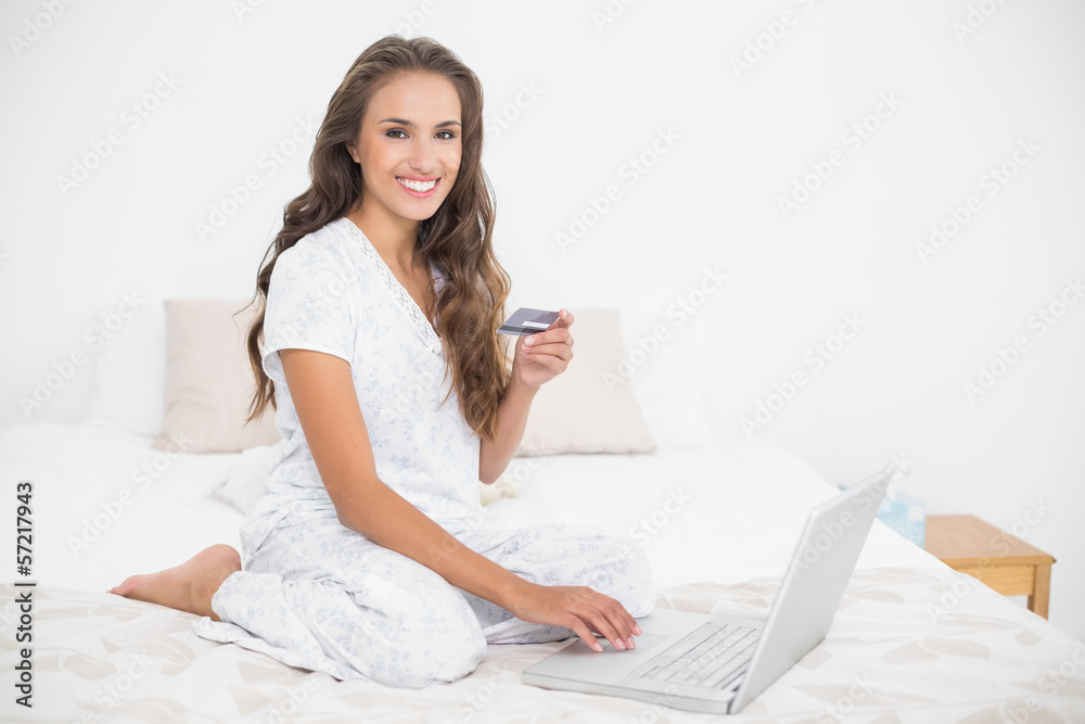 Happy attractive brunette holding credit card and using laptop Happy attractive brunette holding credit card and using laptop