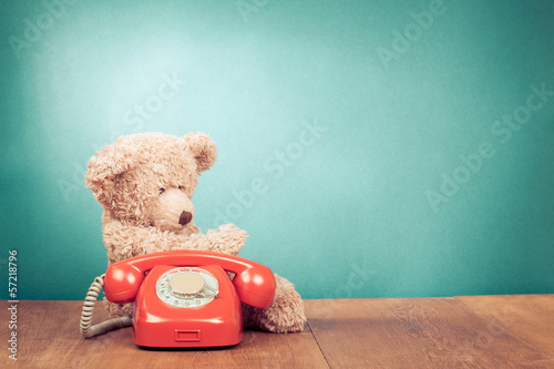 Retro red telephone and Teddy Bear near mint green wall photo