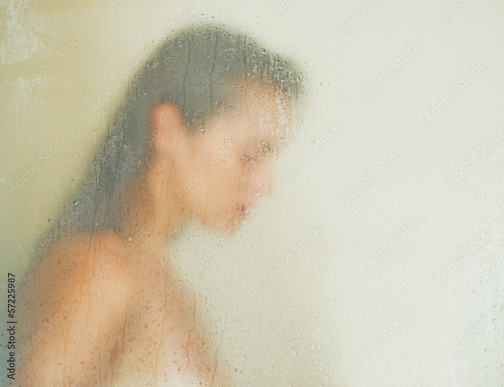 Woman washing behind weeping glass shower door