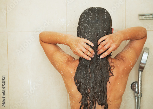 Woman washing hair in shower . rear view