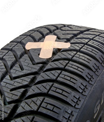 A damaged car tyre with puncture and first aid plaster