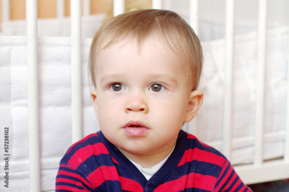 portrait of thoughtful baby boy age of 1 year against white bed