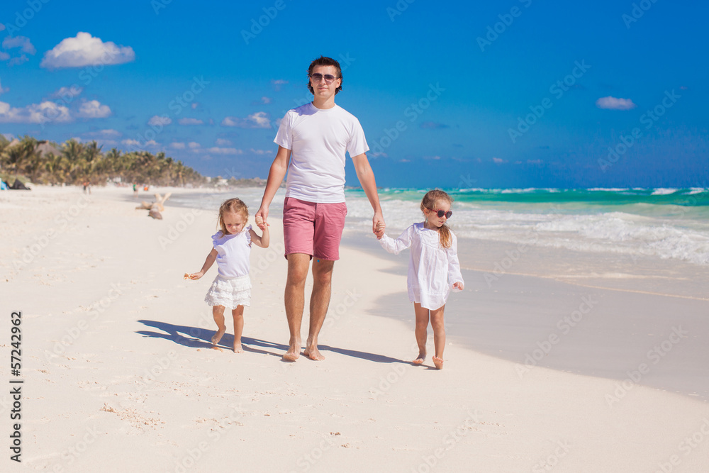 Happy father and his adorable little daughters walking on white